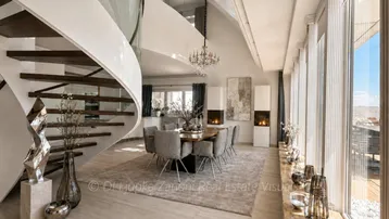 Eleganter Wohn-Essbereich mit geschwungener Treppe, modernen Kaminen und großen Fenstern mit Weitblick.