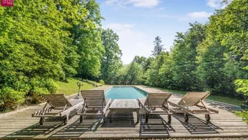Entspannungsbereich am Pool mit Holzliegen und Blick ins Grüne.