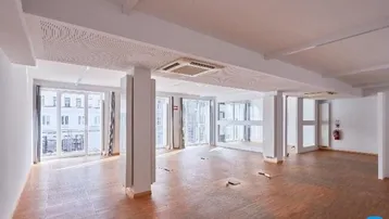 Geräumiger Büroraum mit Holzboden, großen Fenstern und Klimaanlage, ideal für offene Arbeitsbereiche.