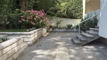 Gepflasterte Terrasse mit Stufen, umgeben von üppigem Grün und blühenden Hortensien.