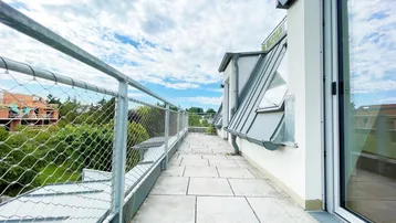 Geräumige Dachterrasse mit Fliesenboden und weitem Blick über die Umgebung.