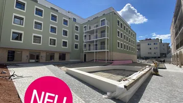Neubauwohngebäude mit moderner Architektur und Baustellenbereich im Vordergrund unter blauem Himmel.
