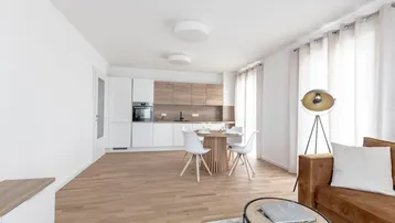 Offener Wohnbereich mit integrierter Küche, Esstisch und hellem Holzboden.