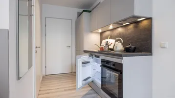 Moderne Küchenzeile mit integrierten Geräten, dunkler Arbeitsplatte und hellem Laminatboden.