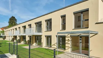 Moderne Wohnanlage mit mehreren Einheiten, Balkonen und Zugang zu begrünten Außenbereichen.