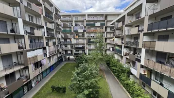 Blick auf den Innenhof eines modernen Wohnkomplexes mit vielen Balkonen und Grünflächen.