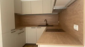 Moderne Einbauküche in Beige- und Holztönen mit Induktionskochfeld, Dunstabzugshaube und viel Stauraum.