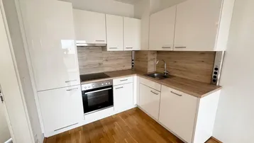 Moderne Einbauküche mit weißen Hochglanzfronten, Holzarbeitsplatte und Parkettboden.