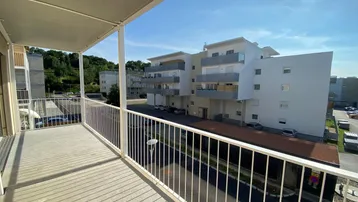 Geräumiger Balkon mit Blick auf die umliegenden Wohngebäude und grüne Hügel.