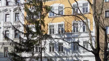 Historisches Mehrfamilienhaus mit klassischer Architektur und gelb-weißer Fassade.