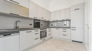 Moderne Einbauküche in Grau mit integrierten Geräten und Fliesenboden.