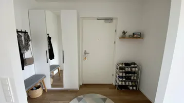 Moderner Eingangsbereich mit weißem Kleiderschrank, Spiegeltüren und hellem Holzfußboden.