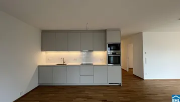 Moderne Einbauküche in Grau mit integrierten Geräten und Holzparkettboden.