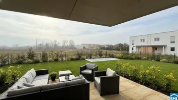 Geräumige Terrasse mit bequemen Gartenmöbeln, Blick auf den grünen Garten und die weite Landschaft.