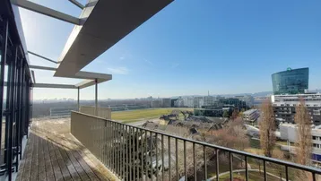 Große Dachterrasse mit Holzboden und weitem Blick über die Stadt und umliegende Gebäude.