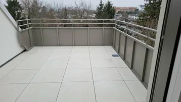 Geräumiger Balkon mit Fliesenboden und Metallgeländer, bietet einen weiten Blick über die Umgebung.