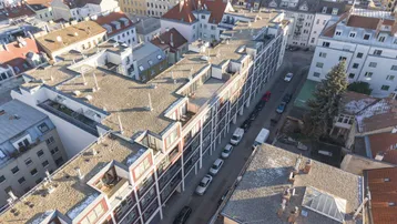 Luftaufnahme eines modernen Wohnkomplexes in städtischer Umgebung mit Flachdächern und umliegenden Gebäuden.