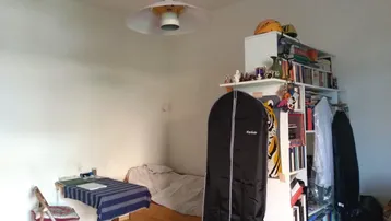 Helles Schlafzimmer mit Holzboden, einem Bett und einem Bücherregal, ideal für Studenten oder Gäste.