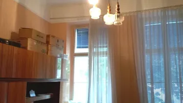 Helles Wohnzimmer mit hohen Decken, einem Sofa und einem Kronleuchter im Altbau.