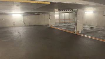 Tiefgarage mit Betonwänden und einem modernen Parkliftsystem für Fahrzeuge.
