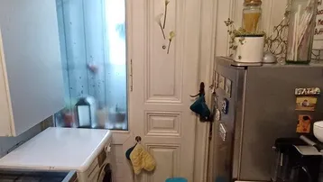 Schmale Küche mit Fenster, Waschmaschine, Herd und Kühlschrank, funktional eingerichtet.
