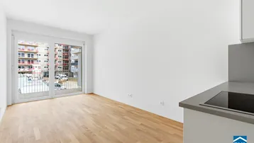 Heller Wohnbereich mit großem Fenster und Zugang zu einem Balkon, Blick auf Neubauten.