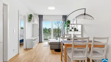 Helles Wohn- und Esszimmer mit Parkettboden, Balkonzugang und moderner Einrichtung.