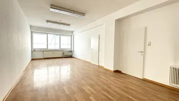 Heller, leerer Raum mit Parkettboden und großen Fenstern, ideal für flexible Nutzung.