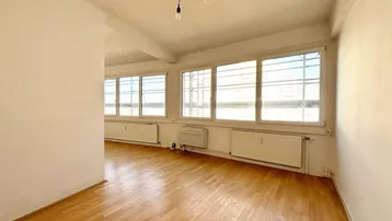 Helles, leeres Zimmer mit Parkettboden und großen Fenstern, bereit zur individuellen Gestaltung.