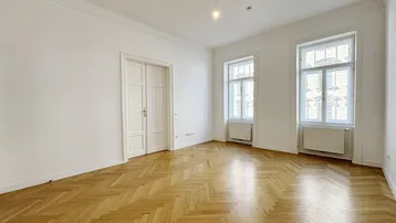 Helles Zimmer mit Fischgrätparkett, hohen Decken und Stuckelementen, ideal als Wohn- oder Schlafzimmer.