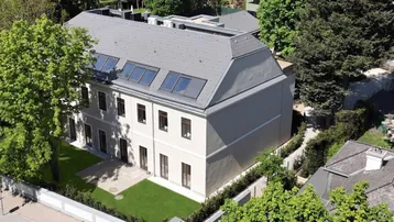 Luftaufnahme eines modernen Neubaus mit Satteldach, Dachfenstern und gepflegtem Gartenbereich.
