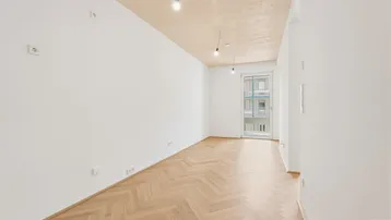 Helles, leeres Zimmer mit Fischgrätparkett und Holzbalkendecke, bereit zur individuellen Gestaltung.