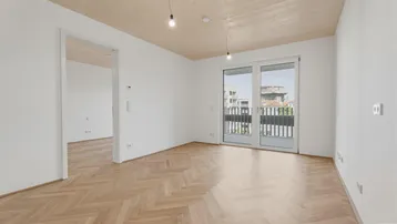 Helles Zimmer mit Fischgrätparkett und Zugang zu einem Balkon, ideal als Wohn- oder Schlafbereich.