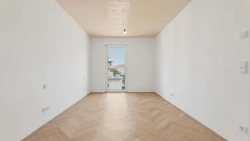 Helles Schlafzimmer mit Fischgrätparkett und Zugang zu einem französischen Balkon.