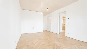 Heller Raum mit Fischgrätparkettboden und Holzbalkendecke, bietet vielseitige Nutzungsmöglichkeiten.