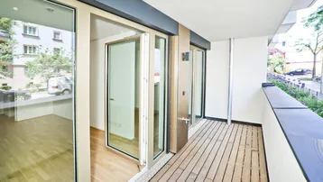 Heller Balkon mit Holzboden und Blick auf die Straße, ideal für entspannte Stunden im Freien.