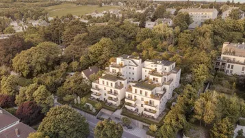 Luftaufnahme eines modernen Wohnkomplexes mit begrünten Dächern und Balkonen in grüner Umgebung.