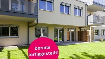 Neubau-Fassade mit Balkonen und direktem Zugang zu privaten Gartenflächen im Erdgeschoss.