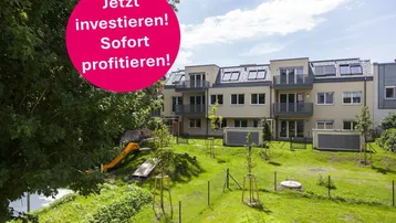 Modernes Mehrfamilienhaus mit Balkonen, Dachfenstern und einem grünen Gartenbereich mit Spielplatz.