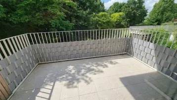 Geräumige Terrasse mit Fliesenboden und Blick ins Grüne, ideal für entspannte Stunden im Freien.
