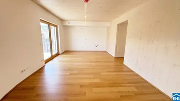 Helles Wohnzimmer mit Holzboden, Holzdecke und Zugang zu einem potenziellen Außenbereich.