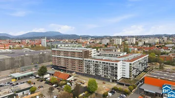 Luftaufnahme einer modernen Wohnanlage in städtischer Umgebung mit Bergen im Hintergrund.