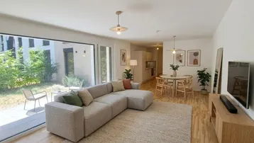 Helles, modern eingerichtetes Wohn-Esszimmer mit Zugang zur Terrasse und Blick ins Grüne.