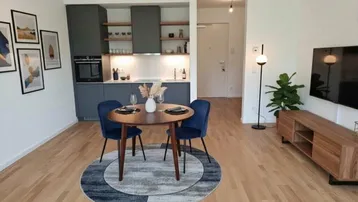Moderne offene Küche mit grauen Schränken, integrierten Geräten und kleinem Essbereich.