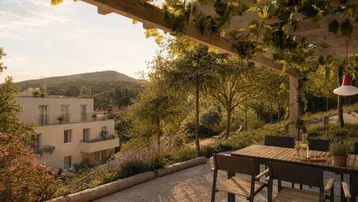 Geräumige Terrasse mit Pergola und Gartenmöbeln, bietet einen weiten Blick auf die umliegende grüne Landschaft und Berge.