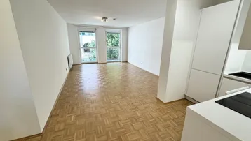 Heller offener Wohnbereich mit Parkettboden und Zugang zu zwei französischen Balkonen.