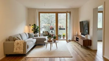 Helles Wohnzimmer mit Holzboden, modernem Sofa und direktem Zugang zum Balkon mit Blick ins Grüne.