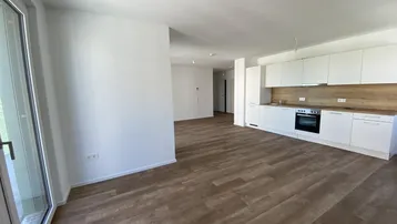 Heller, offener Wohn- und Essbereich mit integrierter Küche und Zugang zum Balkon.