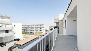 Geräumiger Balkon mit Blick auf die umliegenden modernen Gebäude und den Parkplatz.
