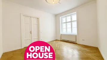 Heller, frisch renovierter Raum mit elegantem Fischgrätparkett, hohen Decken und Stuckelementen.